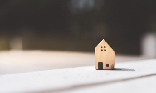 Small,Home,Model,On,Wooden,Table,With,Nature,Green,Bokeh